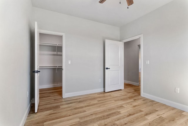 unfurnished bedroom featuring baseboards, a ceiling fan, light wood-style flooring, a walk in closet, and a closet