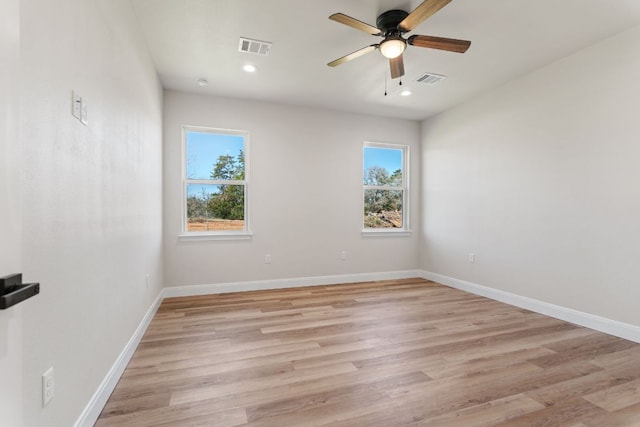 unfurnished room featuring a wealth of natural light, light wood-type flooring, visible vents, and baseboards