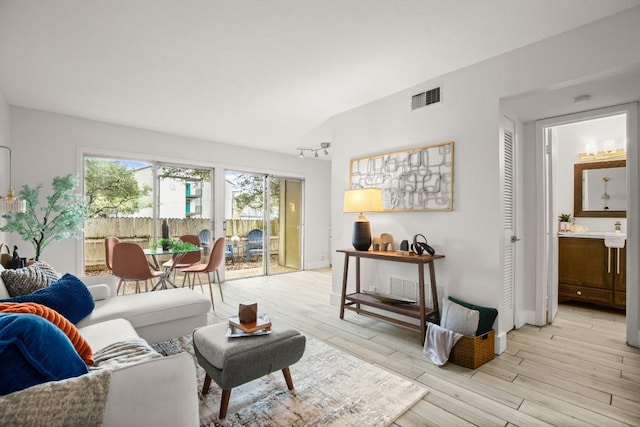 living room with visible vents, light wood-style flooring, and baseboards