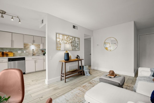 living room with light wood-type flooring, visible vents, and baseboards