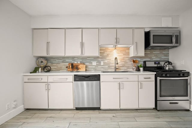 kitchen with a sink, white cabinets, stainless steel appliances, and light countertops