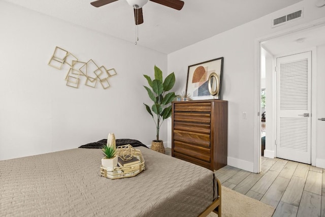 bedroom with ceiling fan, wood finished floors, visible vents, and baseboards