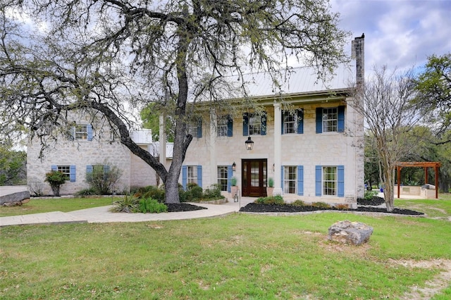 greek revival house featuring metal roof, a chimney, and a front yard