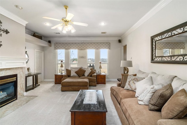 living area with light carpet, baseboards, a ceiling fan, ornamental molding, and a high end fireplace