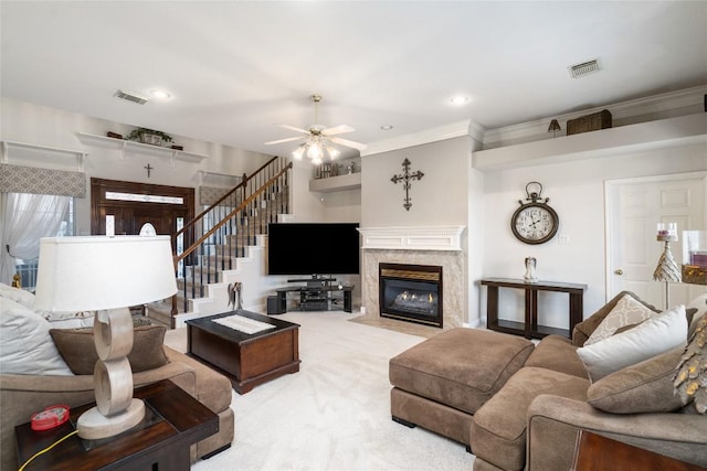 carpeted living room featuring ornamental molding, visible vents, a premium fireplace, and stairs