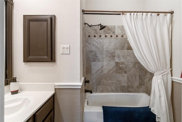 bathroom with shower / bath combo, a textured wall, and vanity