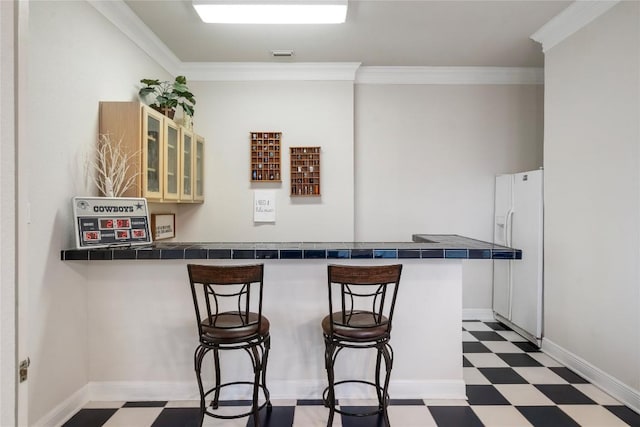 kitchen featuring tile countertops, light floors, and a breakfast bar area