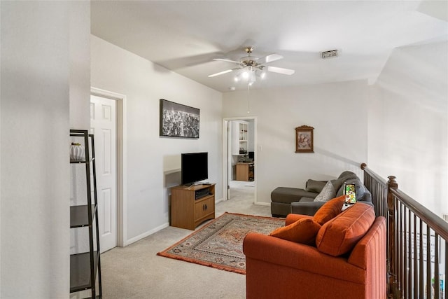 living area with baseboards, ceiling fan, visible vents, and light colored carpet