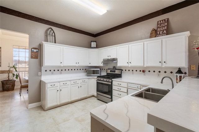 kitchen with a peninsula, under cabinet range hood, a sink, and gas stove