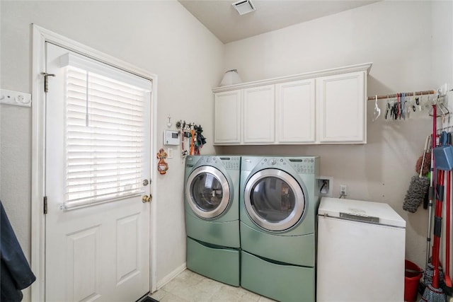 washroom featuring visible vents, washing machine and dryer, and cabinet space