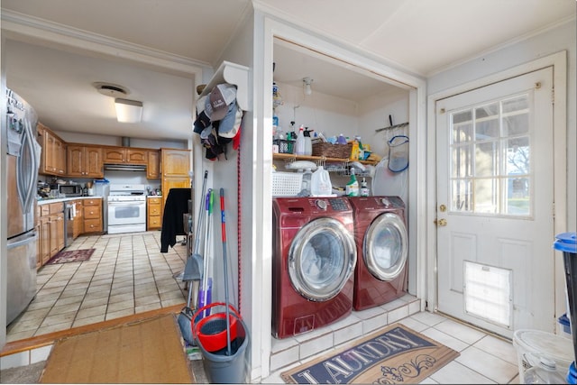 clothes washing area featuring crown molding, washer and clothes dryer, light tile patterned flooring, and laundry area
