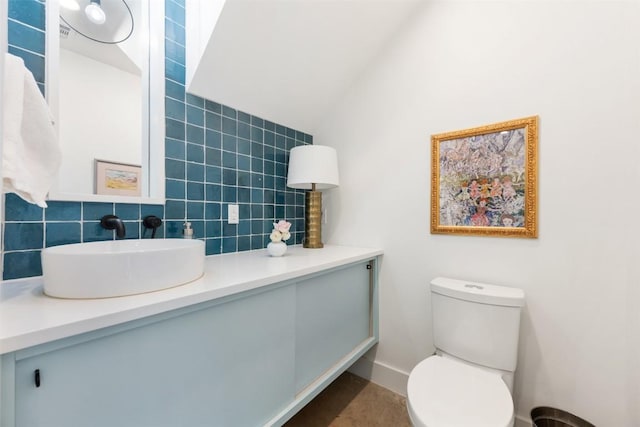 bathroom featuring toilet, tasteful backsplash, vaulted ceiling, and vanity