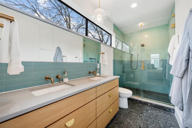 bathroom featuring tasteful backsplash, a sink, toilet, and a shower stall