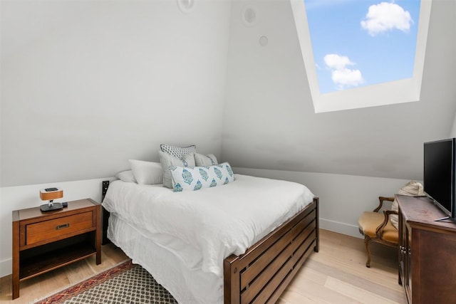 bedroom featuring light wood-type flooring, vaulted ceiling, and baseboards