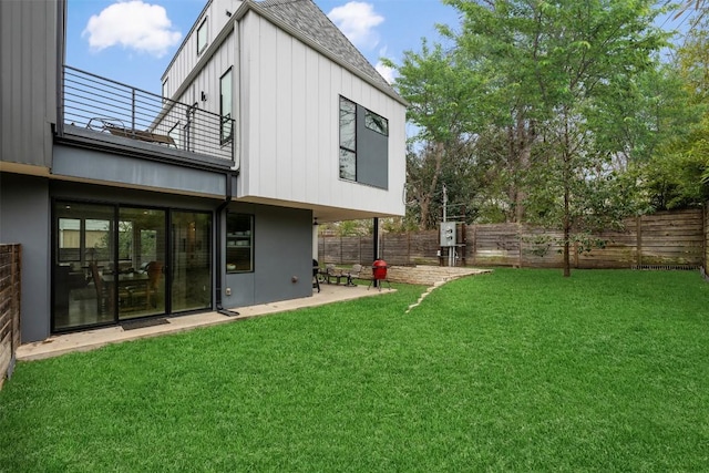 view of yard with a patio area, a fenced backyard, and a balcony