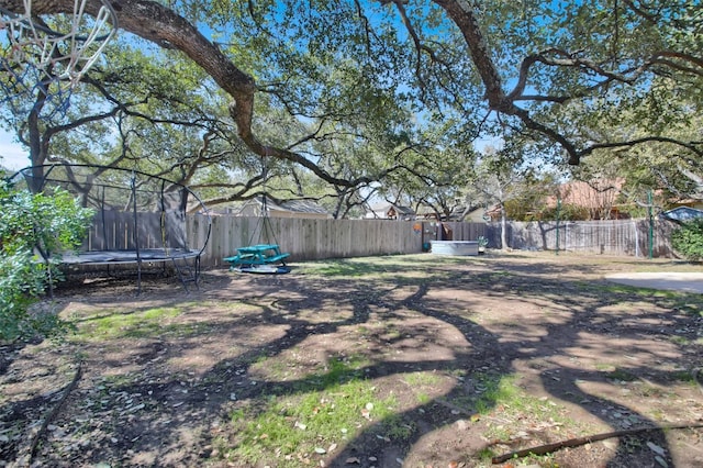 view of yard featuring a trampoline and a fenced backyard