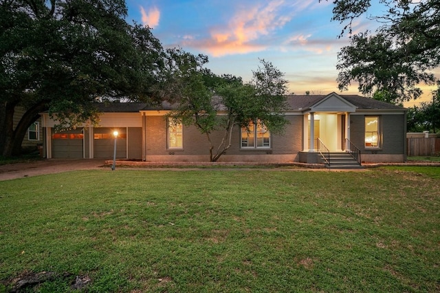 ranch-style home featuring entry steps, driveway, a yard, and an attached garage