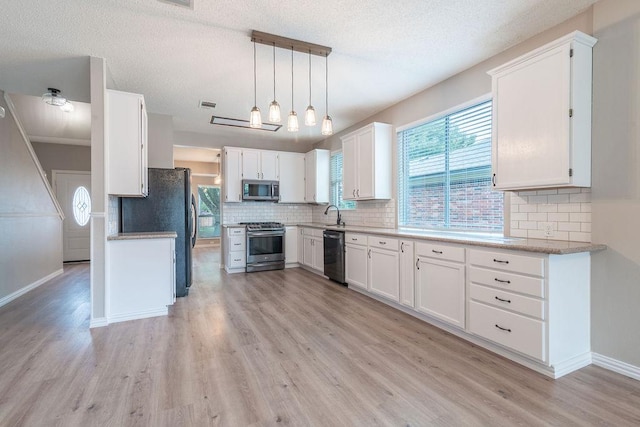 8507 Chat Ln, Round Rock, TX 78681 - kitchen with appliances with stainless steel finishes, light wood-style flooring, decorative backsplash, and a textured ceiling