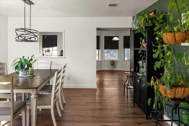 dining area with dark wood finished floors, visible vents, and baseboards