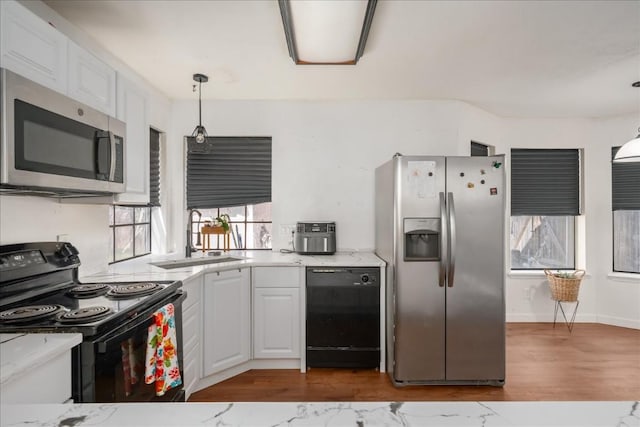 kitchen with white cabinets, light countertops, hanging light fixtures, and black appliances