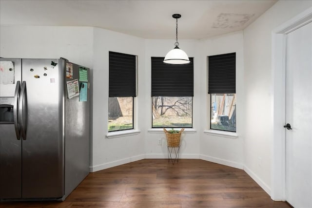 unfurnished dining area with dark wood-type flooring and baseboards