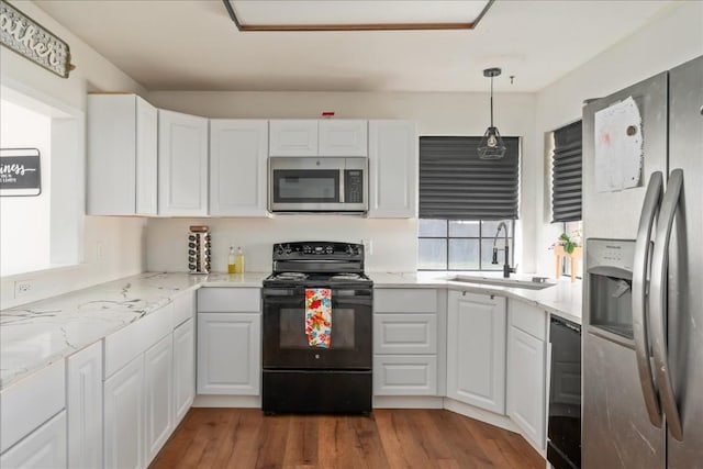 kitchen with black appliances, pendant lighting, white cabinets, and a sink