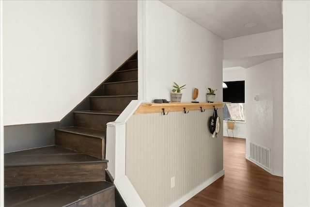 staircase with wood finished floors, visible vents, and baseboards