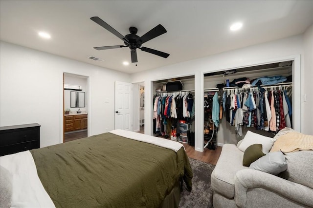 bedroom featuring two closets, visible vents, dark wood-style flooring, and recessed lighting