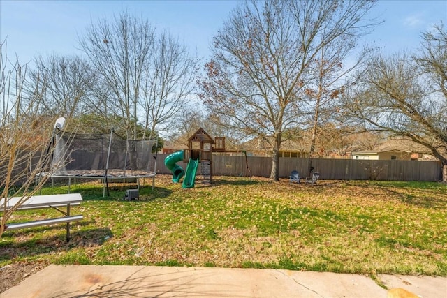 view of yard featuring a trampoline, fence, and a playground