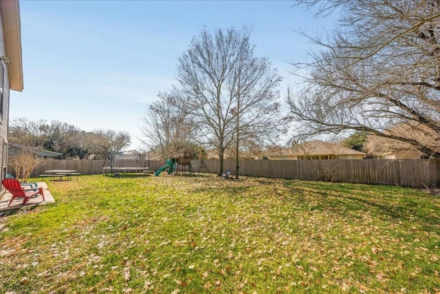 view of yard featuring a trampoline, a playground, and a fenced backyard