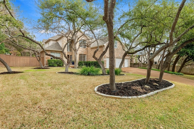 view of yard with driveway, an attached garage, and fence