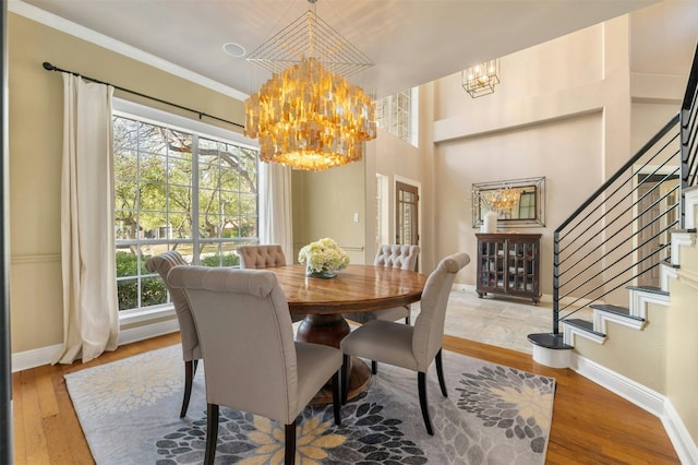 dining room with baseboards, wood finished floors, an inviting chandelier, stairs, and crown molding