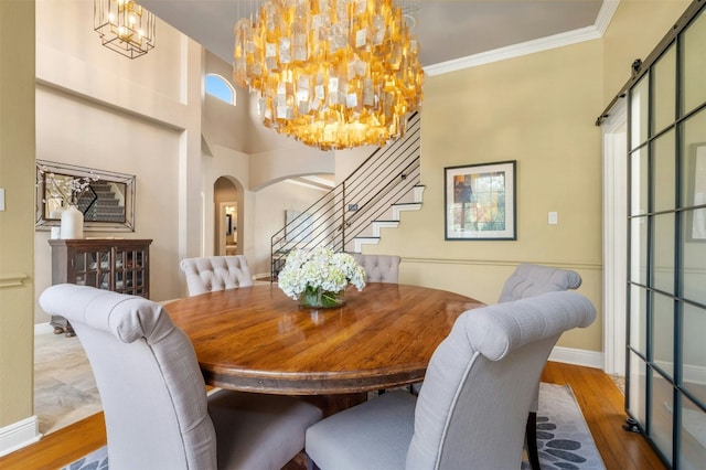 dining space featuring a chandelier, arched walkways, crown molding, and light wood-style flooring