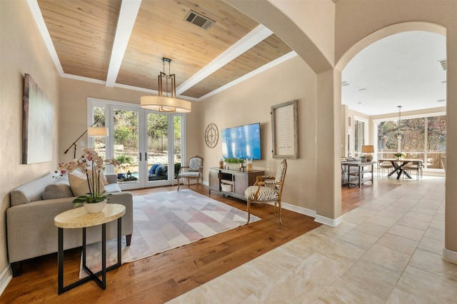 living room with visible vents, light wood-style flooring, wooden ceiling, beamed ceiling, and baseboards