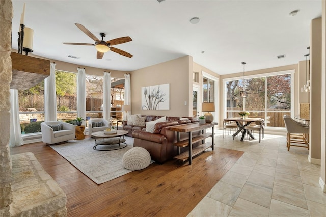 living area with light wood-type flooring, visible vents, and a ceiling fan