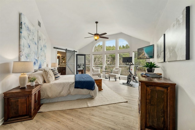 bedroom featuring visible vents, a barn door, light wood-style floors, a ceiling fan, and high vaulted ceiling