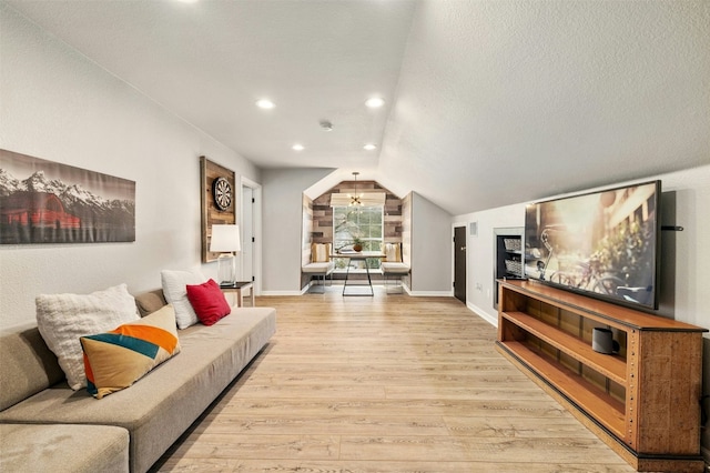 living room featuring lofted ceiling, light wood finished floors, baseboards, and a textured ceiling