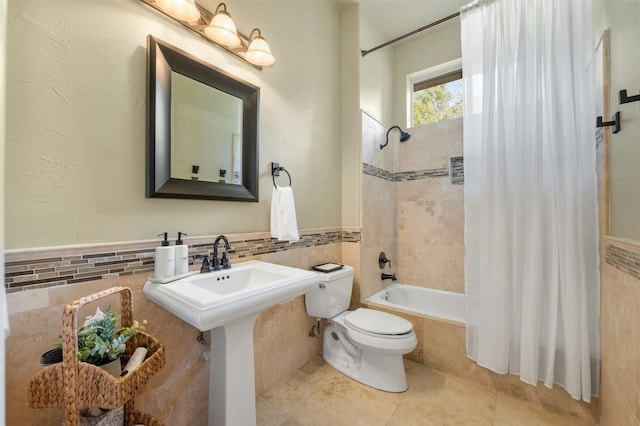 full bathroom with toilet, tiled shower / bath combo, a sink, tile walls, and tile patterned floors