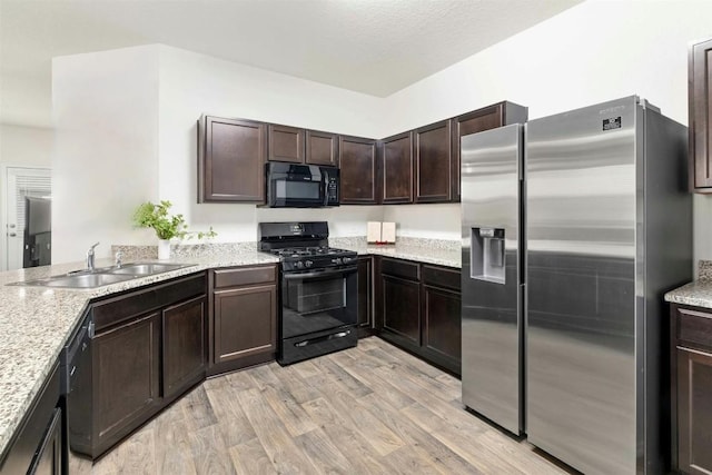 kitchen featuring dark brown cabinetry, light wood-style floors, a textured ceiling, black appliances, and a sink