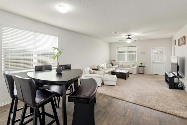 dining area with dark wood-type flooring, plenty of natural light, a textured ceiling, and ceiling fan