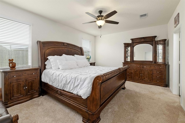 bedroom with a ceiling fan, visible vents, and light colored carpet