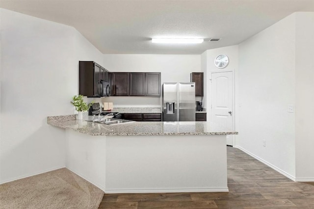 kitchen featuring dark brown cabinetry, stainless steel fridge, wood finished floors, black microwave, and a sink