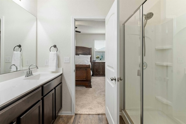 ensuite bathroom with a stall shower, connected bathroom, vanity, and wood finished floors