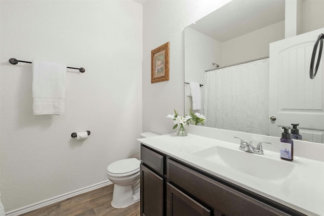 full bathroom with toilet, baseboards, wood finished floors, and vanity