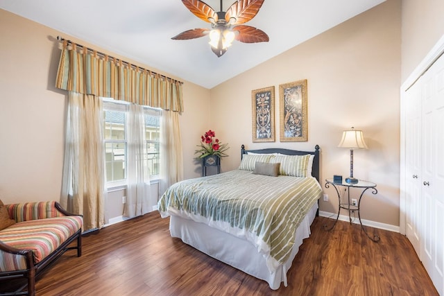 bedroom with lofted ceiling, dark wood-type flooring, a closet, and baseboards