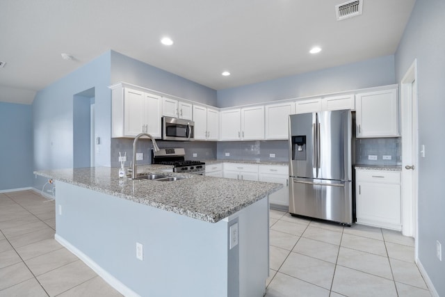 kitchen with light stone counters, visible vents, appliances with stainless steel finishes, white cabinets, and a peninsula