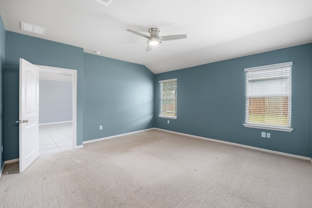 spare room featuring visible vents, baseboards, a ceiling fan, light colored carpet, and lofted ceiling