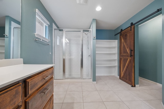 full bath with a stall shower, baseboards, tile patterned floors, a walk in closet, and vanity