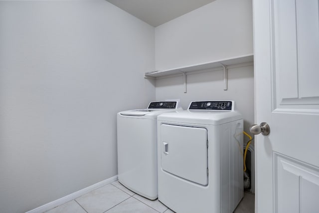 laundry room with light tile patterned floors, laundry area, separate washer and dryer, and baseboards