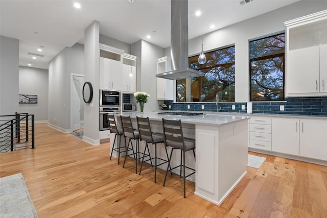 4907 Timberline Dr, Austin, TX 78746 - kitchen featuring island exhaust hood, a kitchen island, backsplash, stainless steel appliances, and recessed lighting